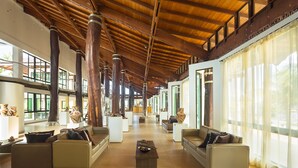 Un hall d’entrée spacieux, doté de hauts plafonds, de poutres en bois et de grandes fenêtres.