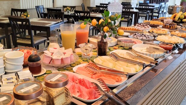 A buffet with various food items and beverages, including fruits, cheeses, and a juice dispenser. - Sandrin Praia Hotel (Aracaju)
