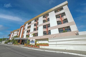 Un hotel de varios pisos con diseño moderno, que cuenta con balcones y un acceso cubierto.