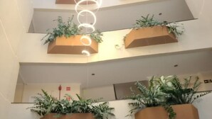 A multi-level atrium with tiered planters containing greenery, a modern light fixture, and a visible fire alarm. - Sandrin Praia Hotel (Aracaju)