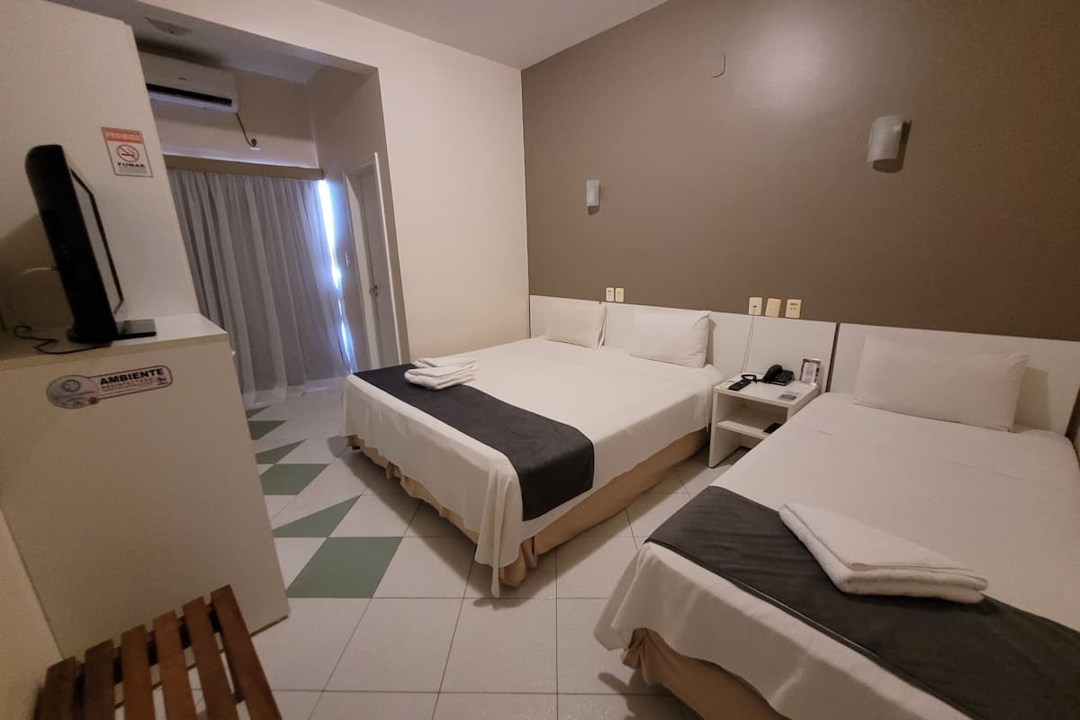 Una habitación de hotel con dos camas, un escritorio, una silla y un televisor.