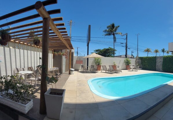 Un jardin avec une piscine, un espace salon extérieur et une pergola.
