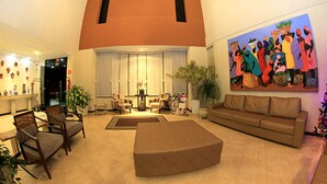 A spacious lobby with a high ceiling, a large sofa, a coffee table, and a painting on the wall. - Sandrin Praia Hotel (Aracaju)