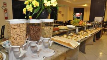 A buffet with various food items and a flower arrangement.