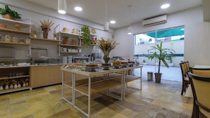 A spacious kitchen with a long counter, shelves with kitchenware, and potted plants. - Rio Branco Apart Hotel (Florianópolis)