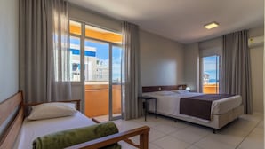 A hotel room with two beds, a balcony, and a view of buildings. - Rio Branco Apart Hotel (Florianópolis)