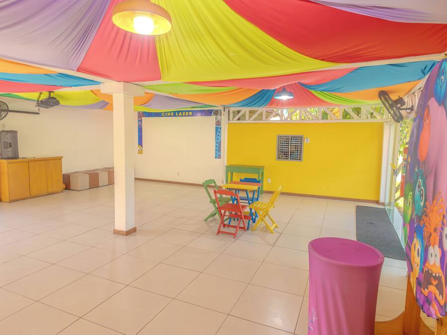 Amplia habitación con piso de baldosas, techo adornado con telas de colores y pared amarilla.