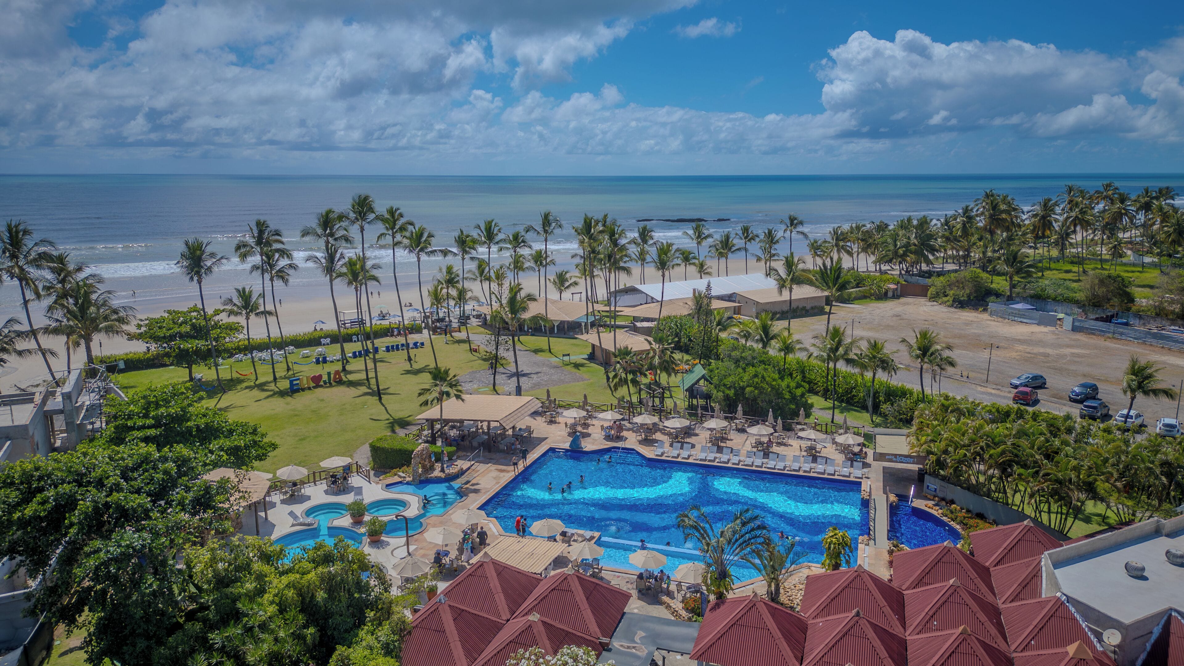 Un resort con piscina, playa y palmeras.