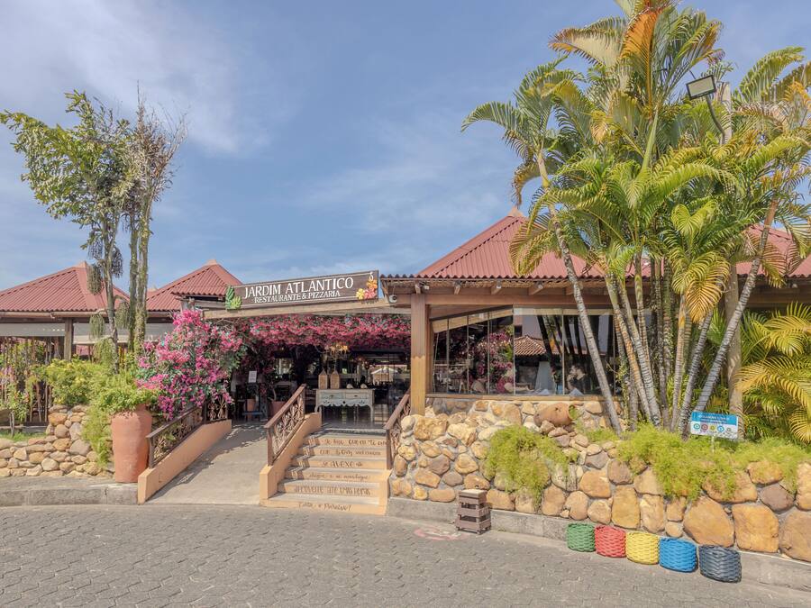 En restaurang med en fasad av sten, en skylt med texten ”JARDIM ATLANTICO RESTAURANT & PIZZERIA” och en trappa som leder upp till entrén.