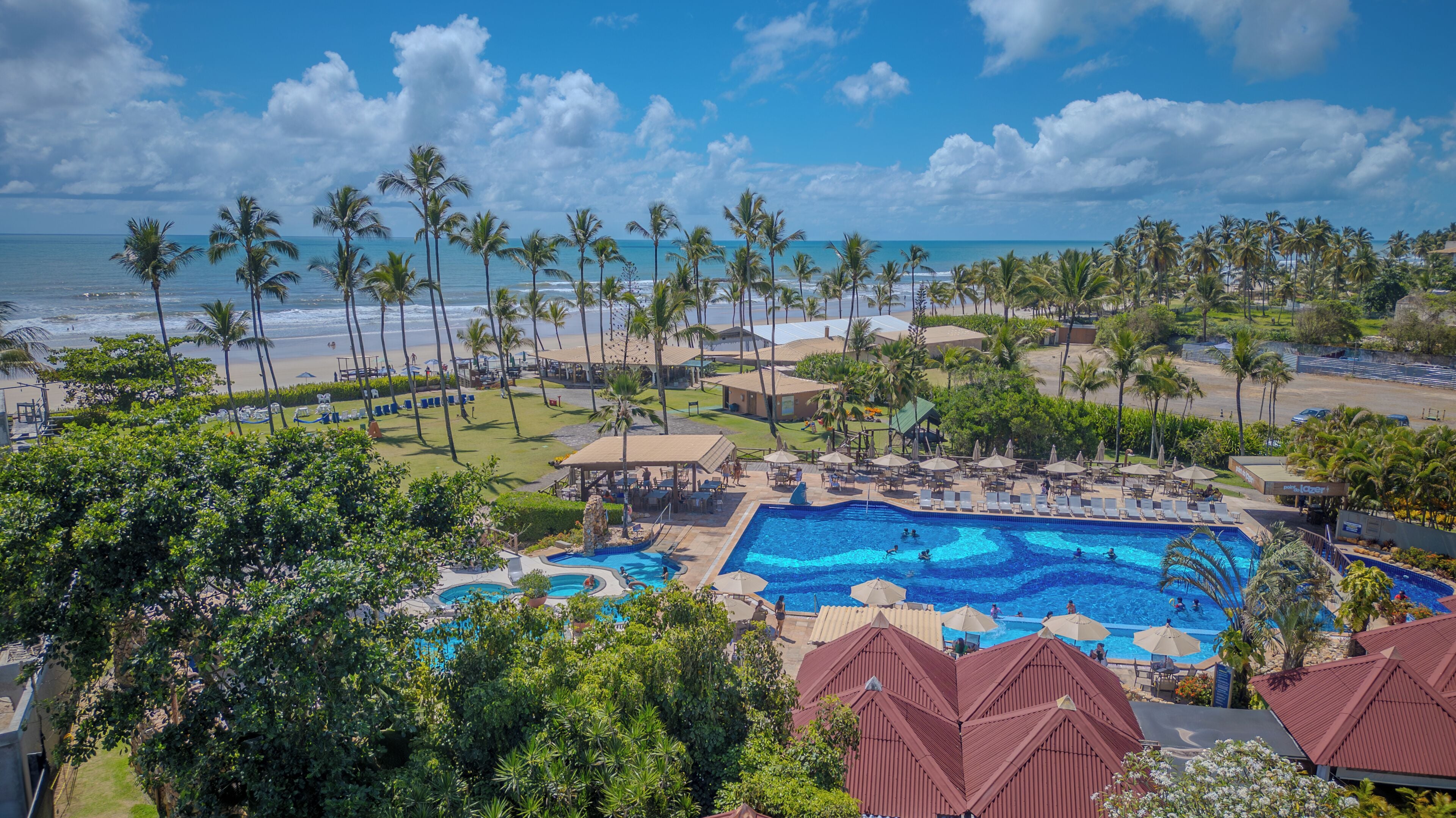 Um resort com piscina, praia e palmeiras.
