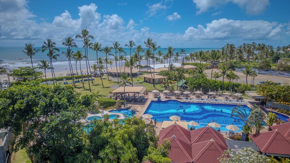 A resort with a swimming pool, beach, and palm trees.