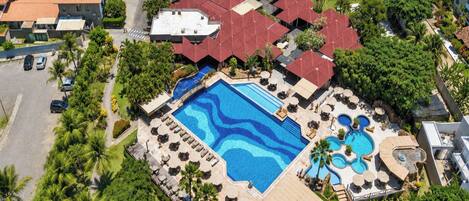 Un resort con varias piscinas, cancha de tenis y un césped bien cuidado.