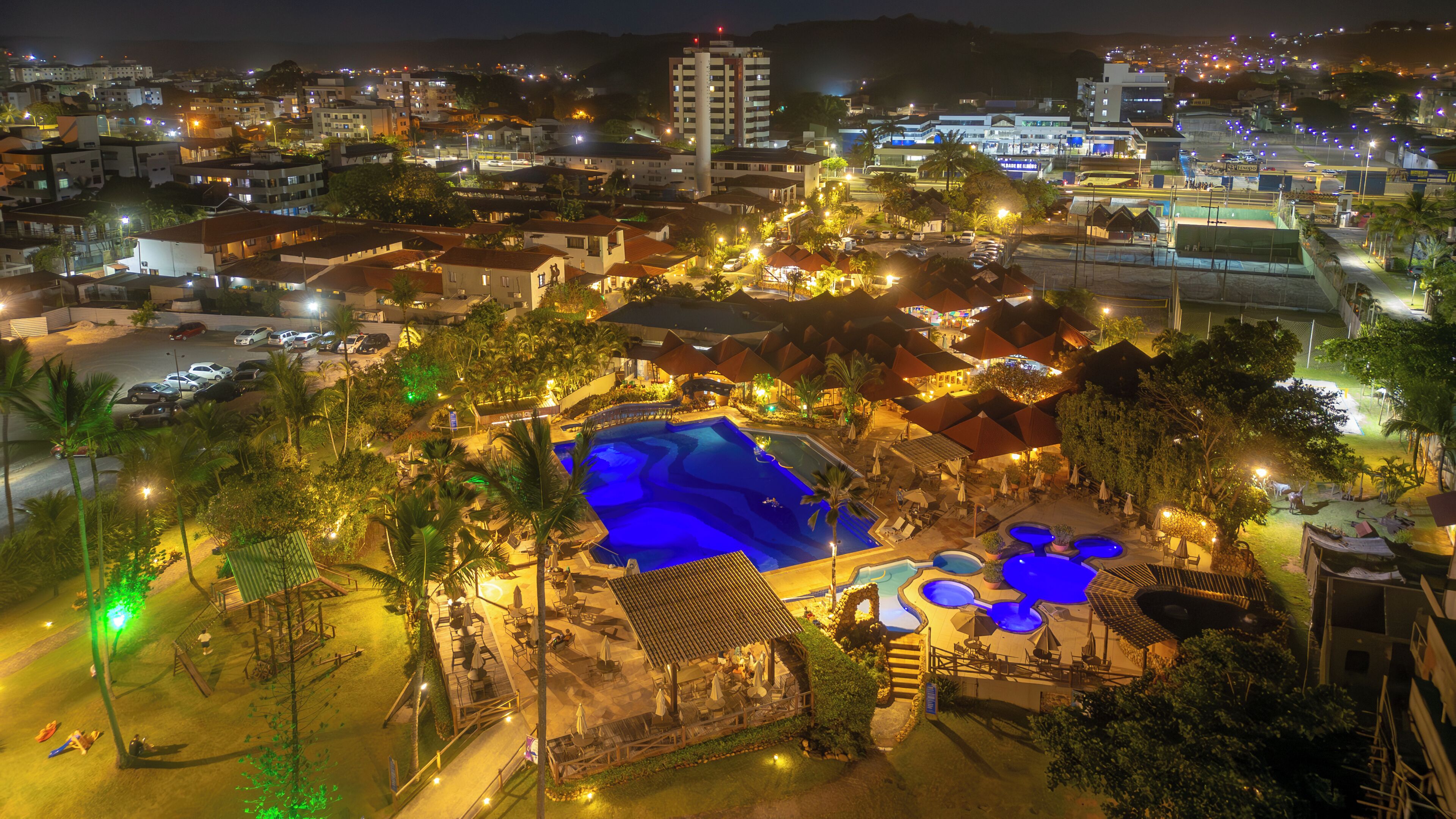 A resort with a swimming pool, outdoor seating, and a view of the surrounding cityscape.