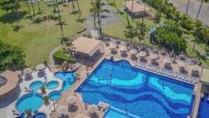Un resort con una piscina grande, playa y palmeras.