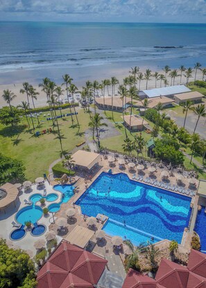 A resort with a large pool, beach, and palm trees.