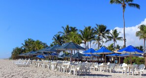 En la playa, arena blanca, sillas reclinables de playa, sombrillas