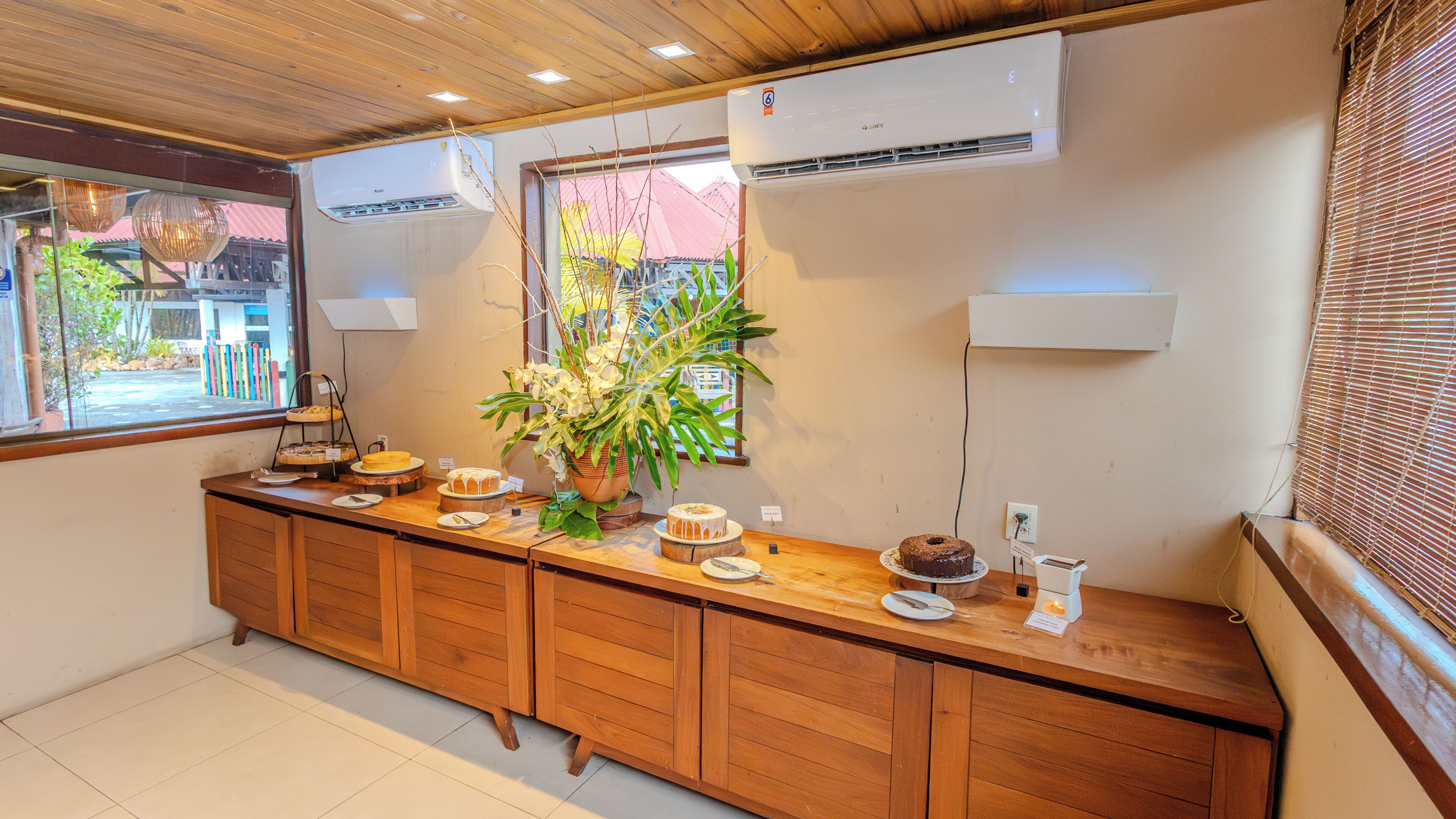 Habitación de hotel con un mostrador tipo buffet de madera, unidades de aire acondicionado y una ventana con vistas al exterior.