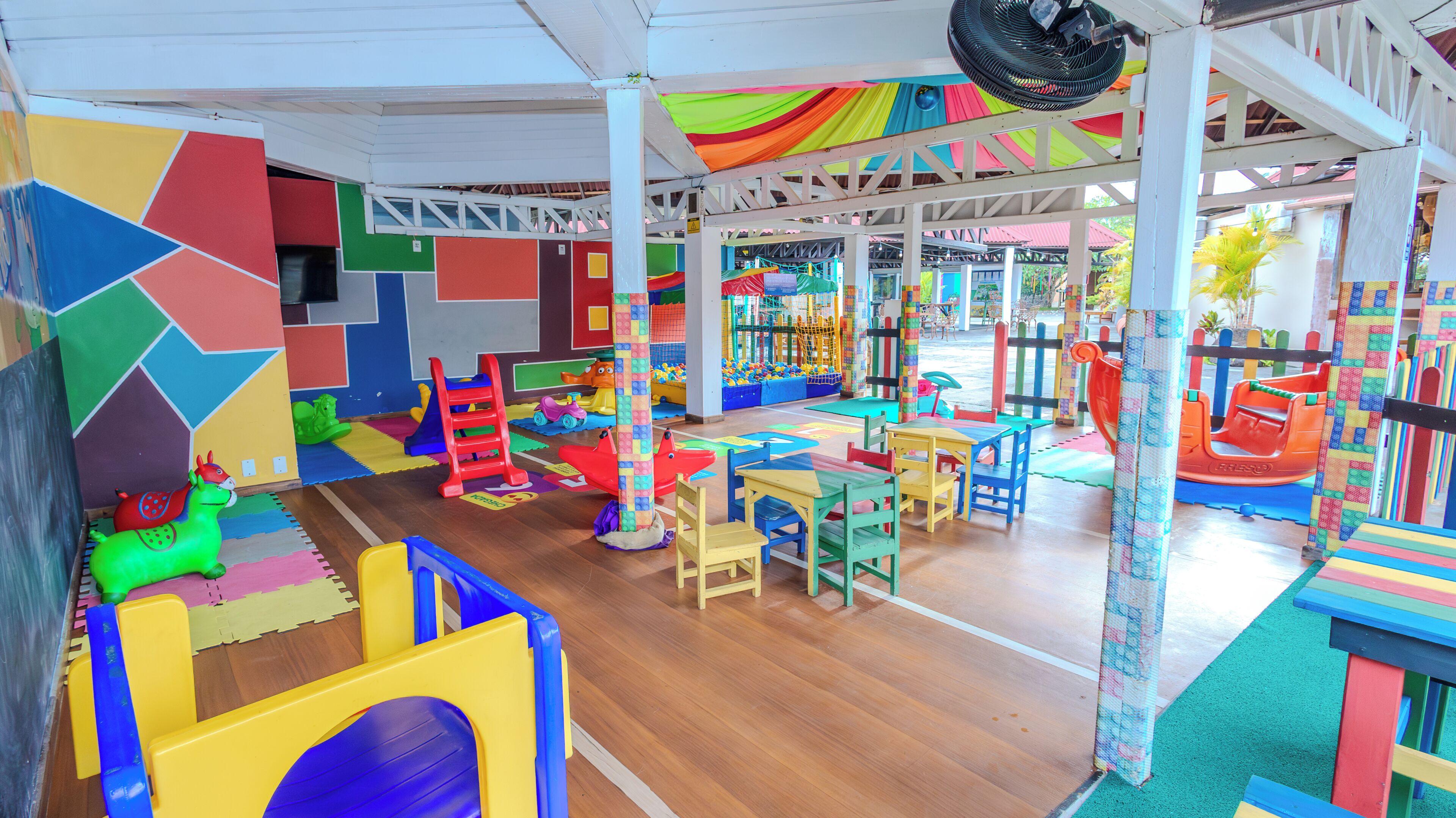 A children's play area with colorful play structures, tables, and chairs.
