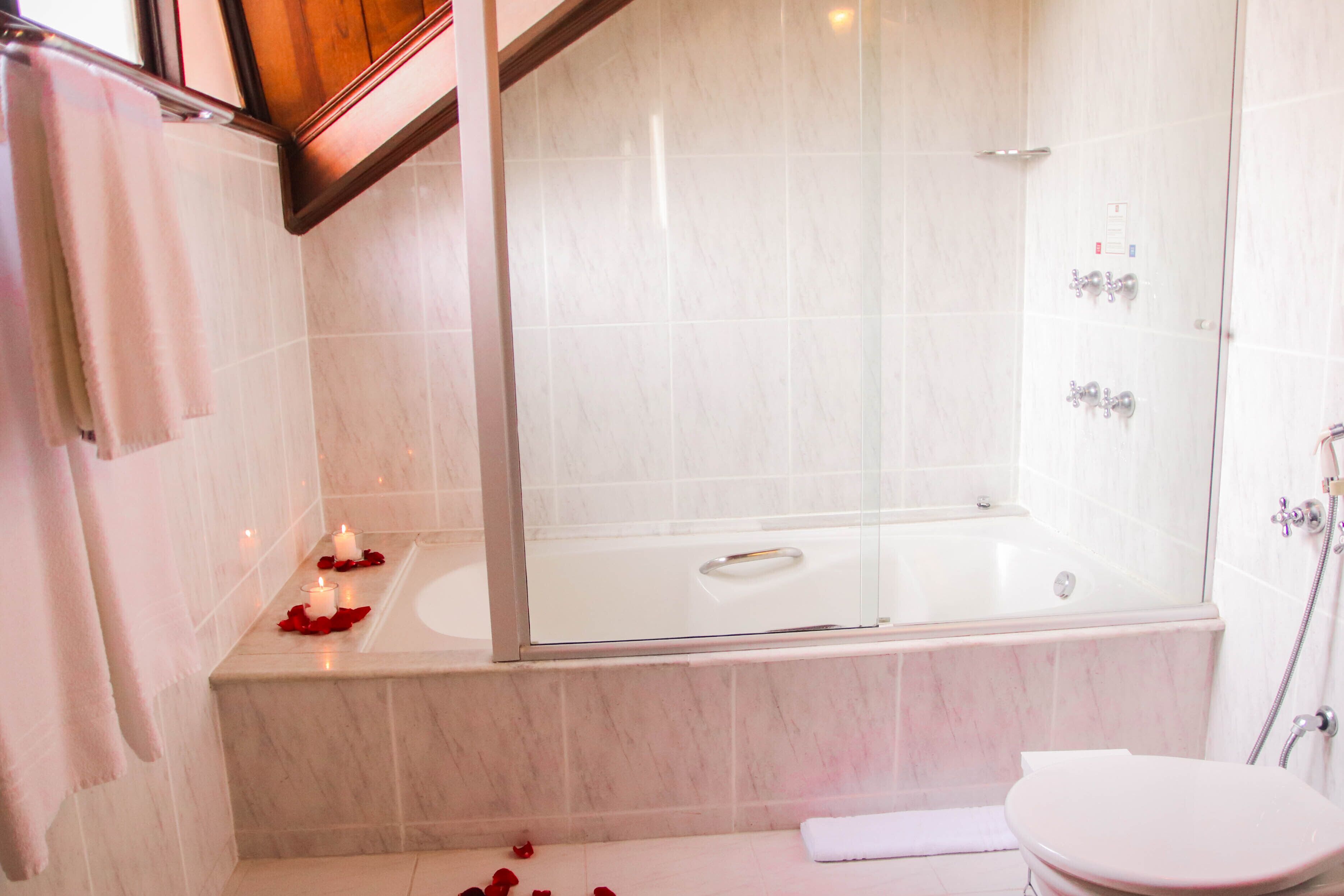 A bathroom with a bathtub, a toilet, and a shower area.