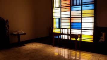 Relax in a serene space with a large stained glass window, a comfortable chair, and a small table.