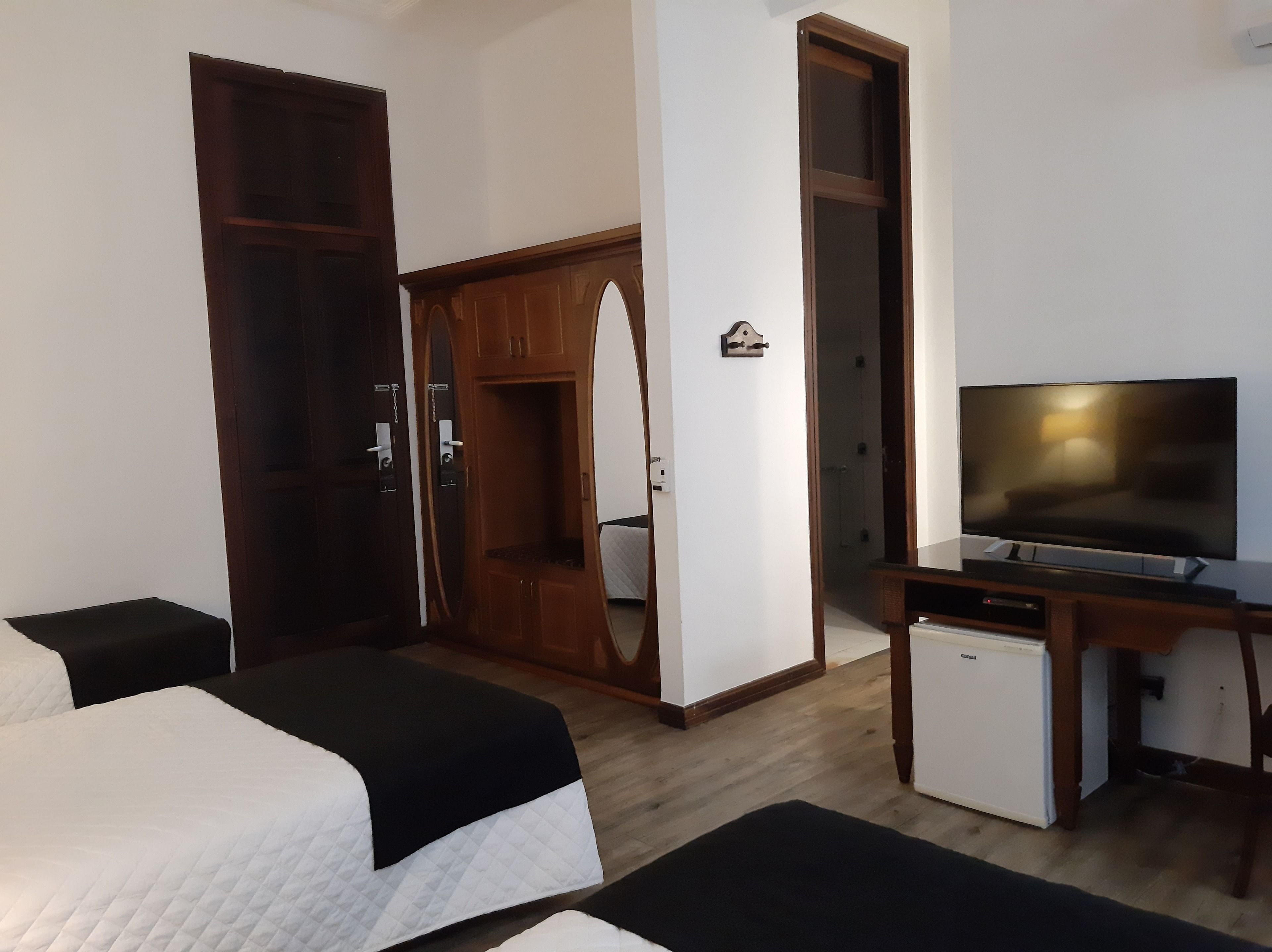 Habitació d'hotel amb un llit, un escriptori amb televisió, un frigorífic petit i un armari.