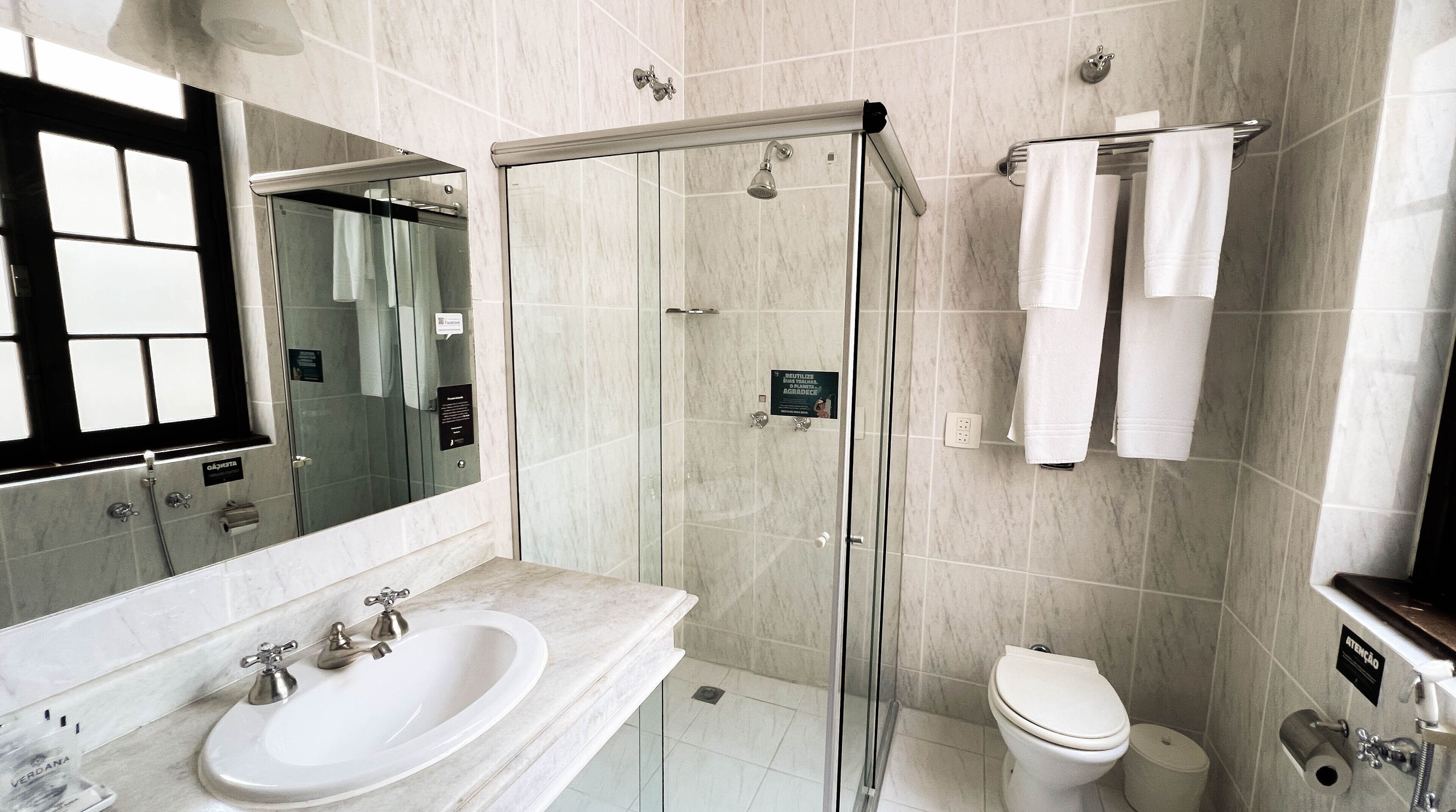 A modern bathroom with a glass-enclosed shower, a double sink vanity, and a toilet.