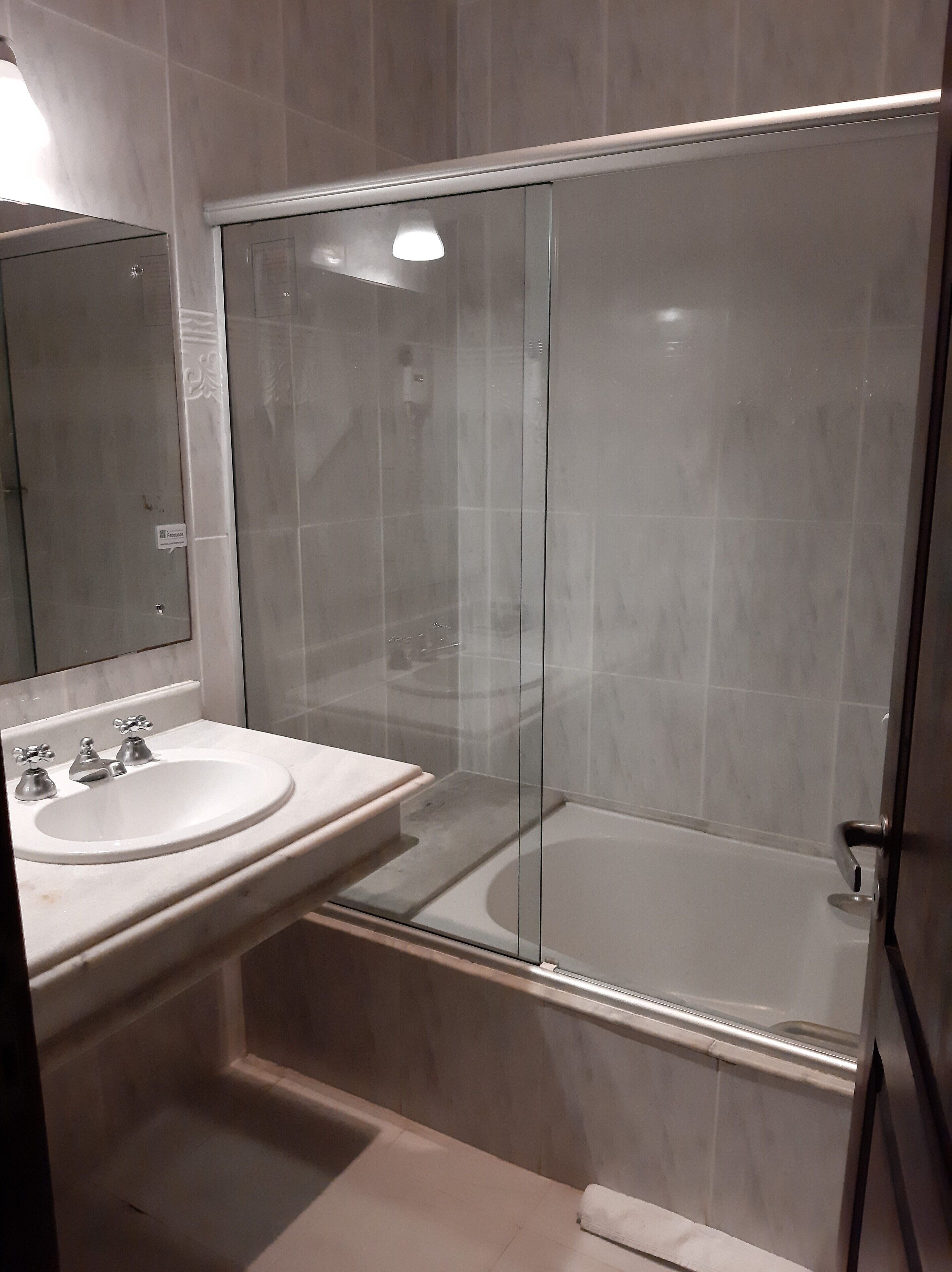 A modern bathroom with two sinks, a glass-enclosed shower, and a large mirror.