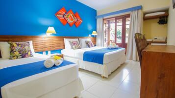 A hotel room with two beds, a wooden headboard, a desk, and a window with curtains.
