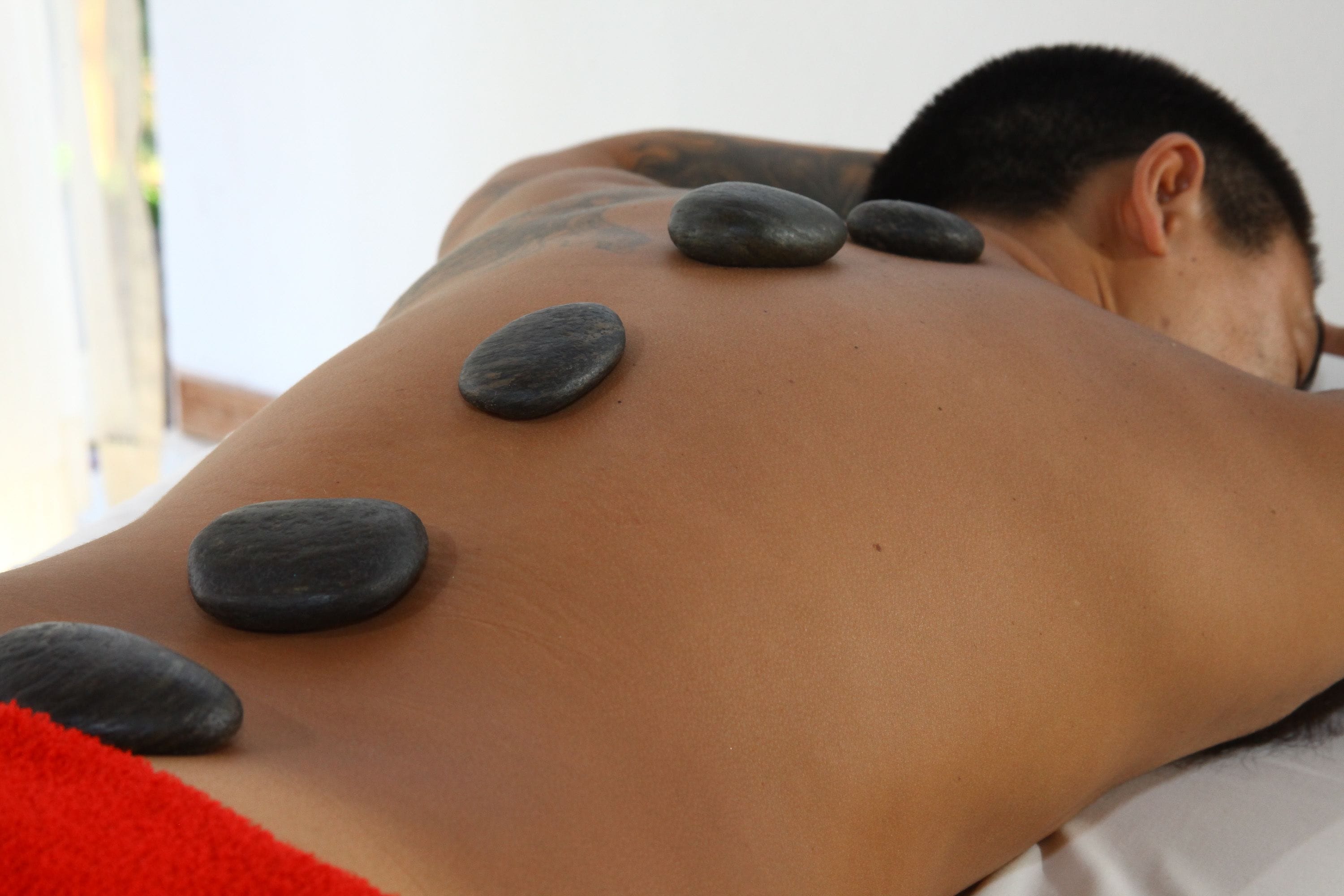 A person receiving a back massage with stones placed on their back.
