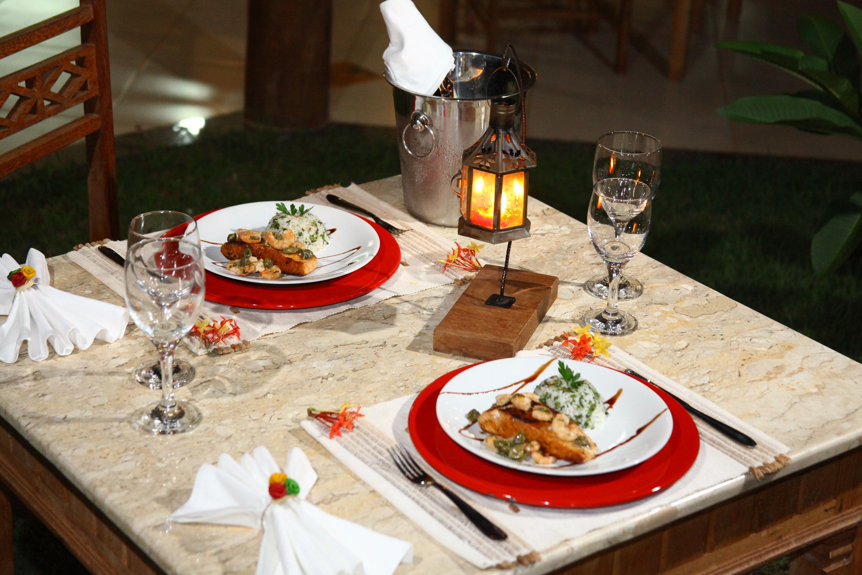 A dining table set with plates, cutlery, glasses, and a candle holder.