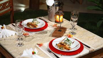 A dining table set with plates, cutlery, glasses, and a candle holder.