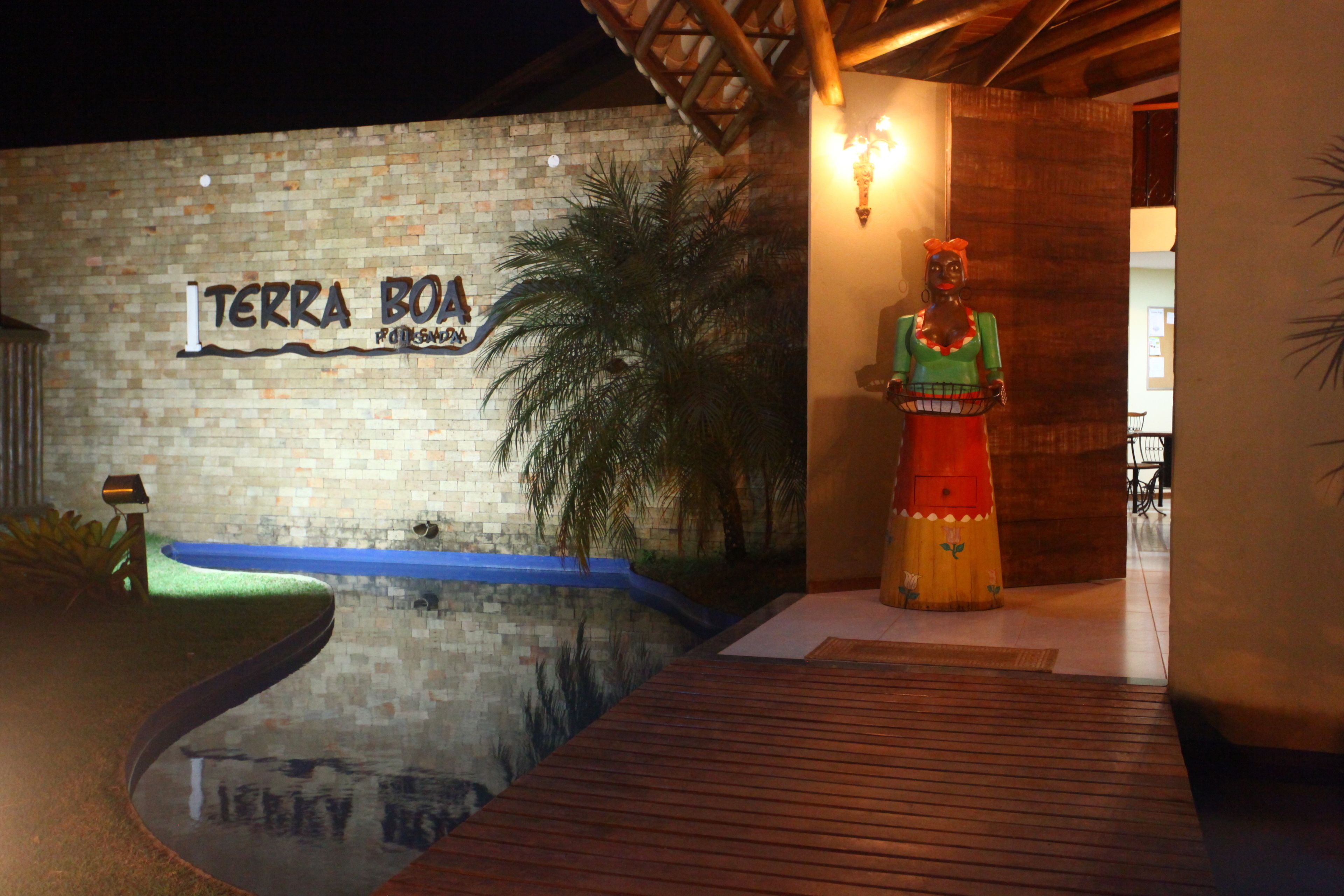 Un muro in mattoni con un cartello che riporta la scritta "TERRA BOA" e una statua di una donna in abiti tradizionali.