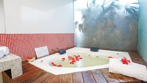 A spa room with a hot tub, red tiled walls, wooden flooring, and a view of palm trees. - Terra Boa Hotel Boutique (Itacaré)