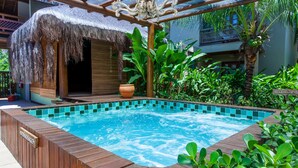 A pool area with a wooden deck, a thatched-roof structure, and lush greenery. - Terra Boa Hotel Boutique (Itacaré)