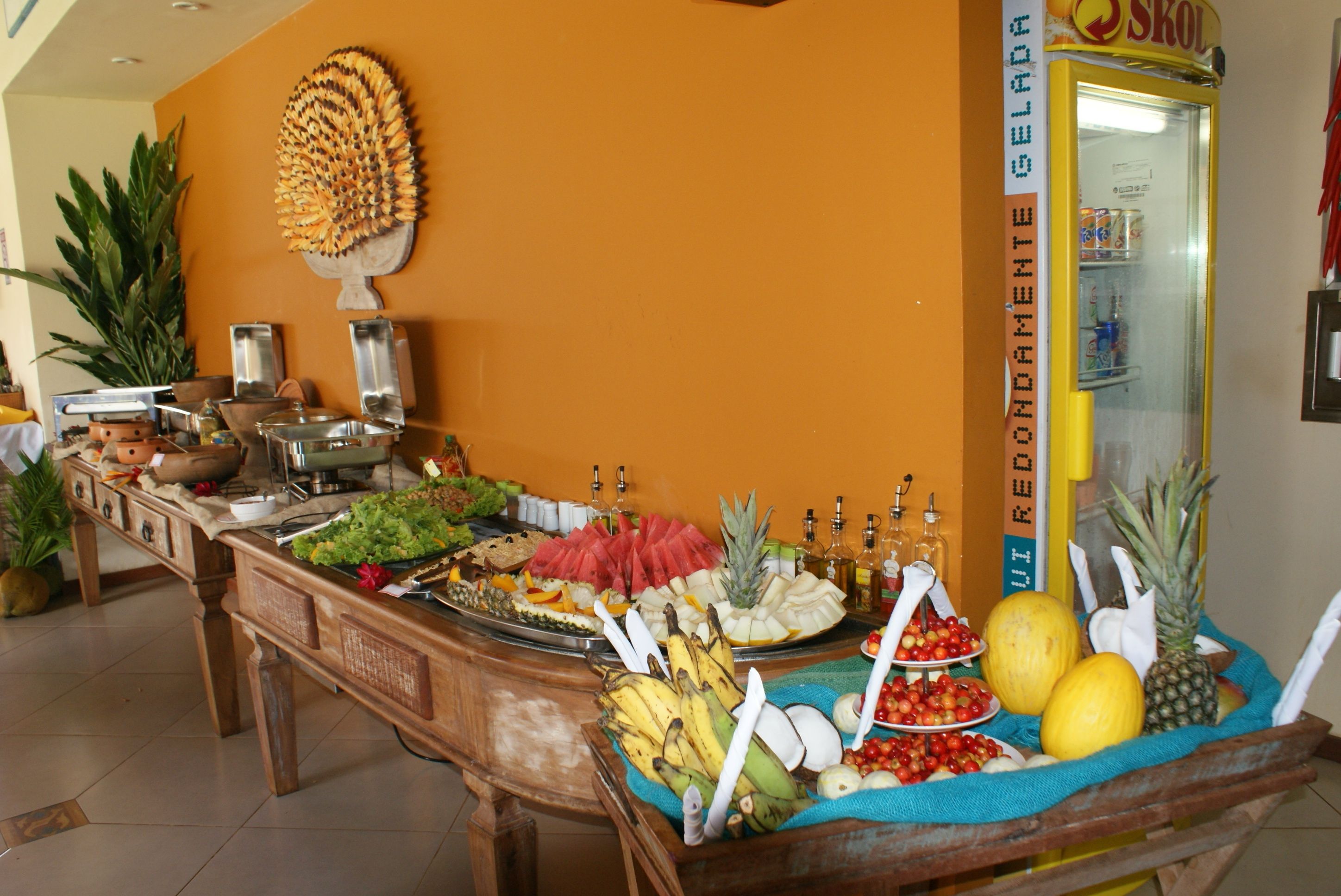 Une table de buffet garnie de divers fruits et légumes, un réfrigérateur et un élément décoratif mural.