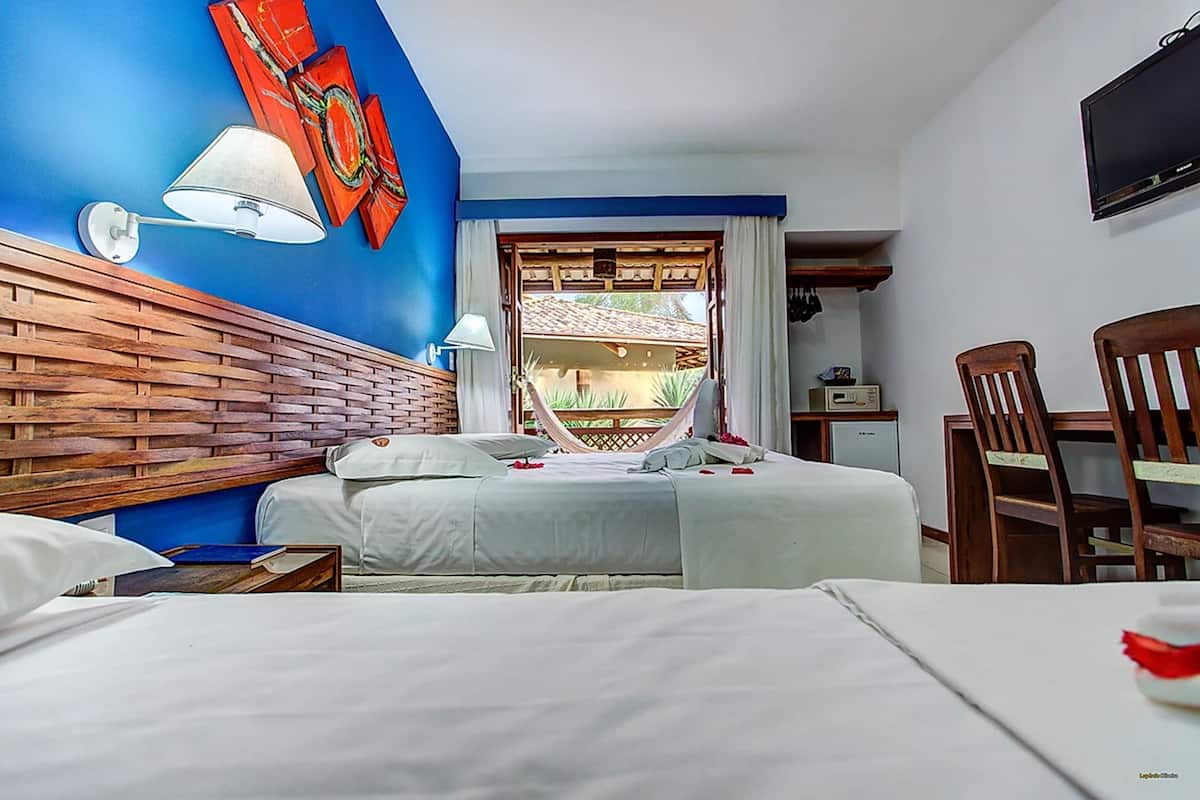 Camera d'albergo con due letti, una testiera in legno, una TV, una scrivania e vista all'esterno.