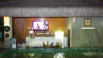 Una zona de bar con una pantalla de televisión, una fuente de agua y un refrigerador.