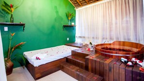 A spa room with a wooden bathtub, a massage table, and a green wall. - Terra Boa Hotel Boutique (Itacaré)