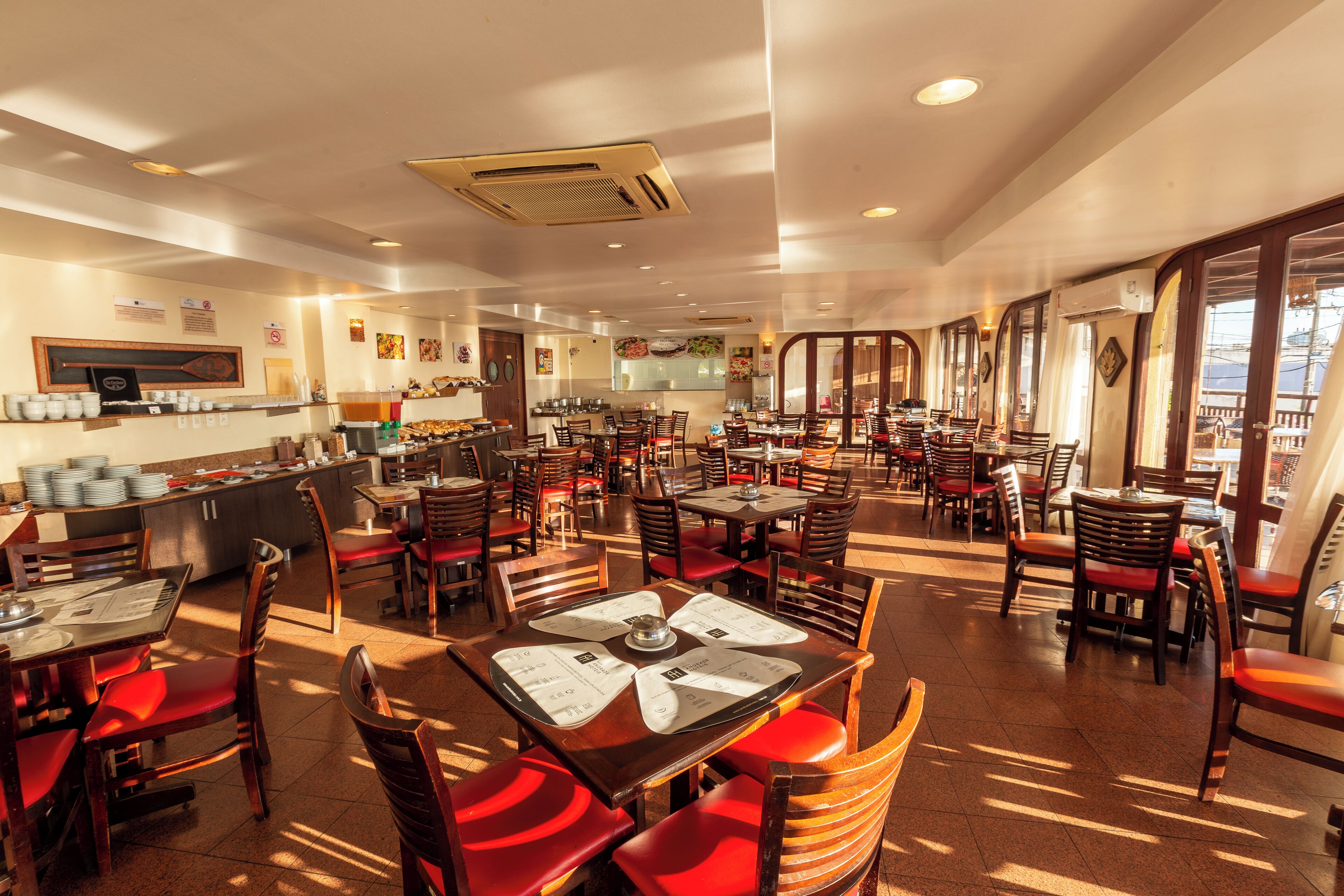 Un restaurant spacieux avec de nombreuses tables et chaises, un espace buffet et une cuisine située à l’arrière.