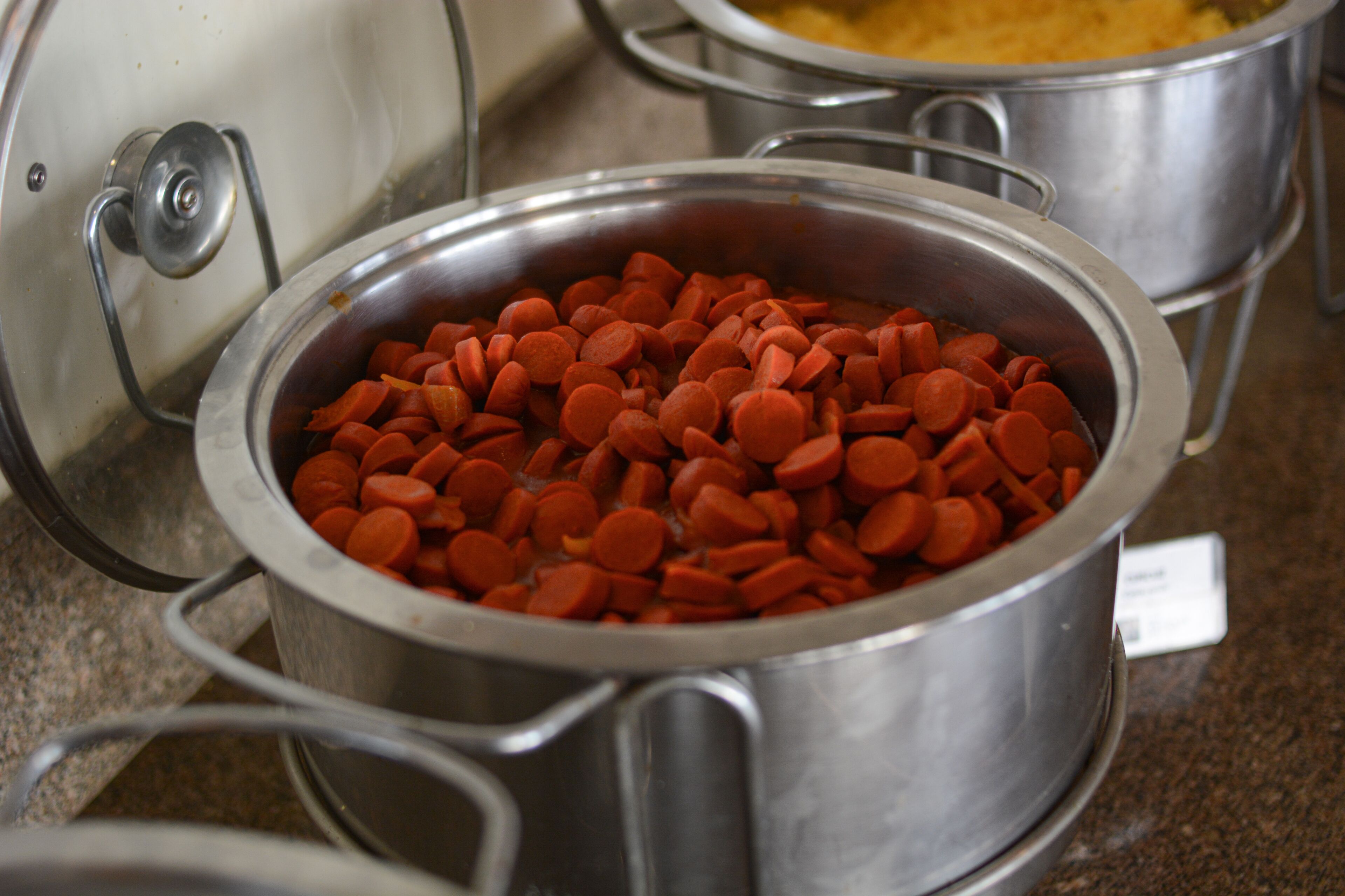 A stainless steel pot filled with red carrots on a countertop.