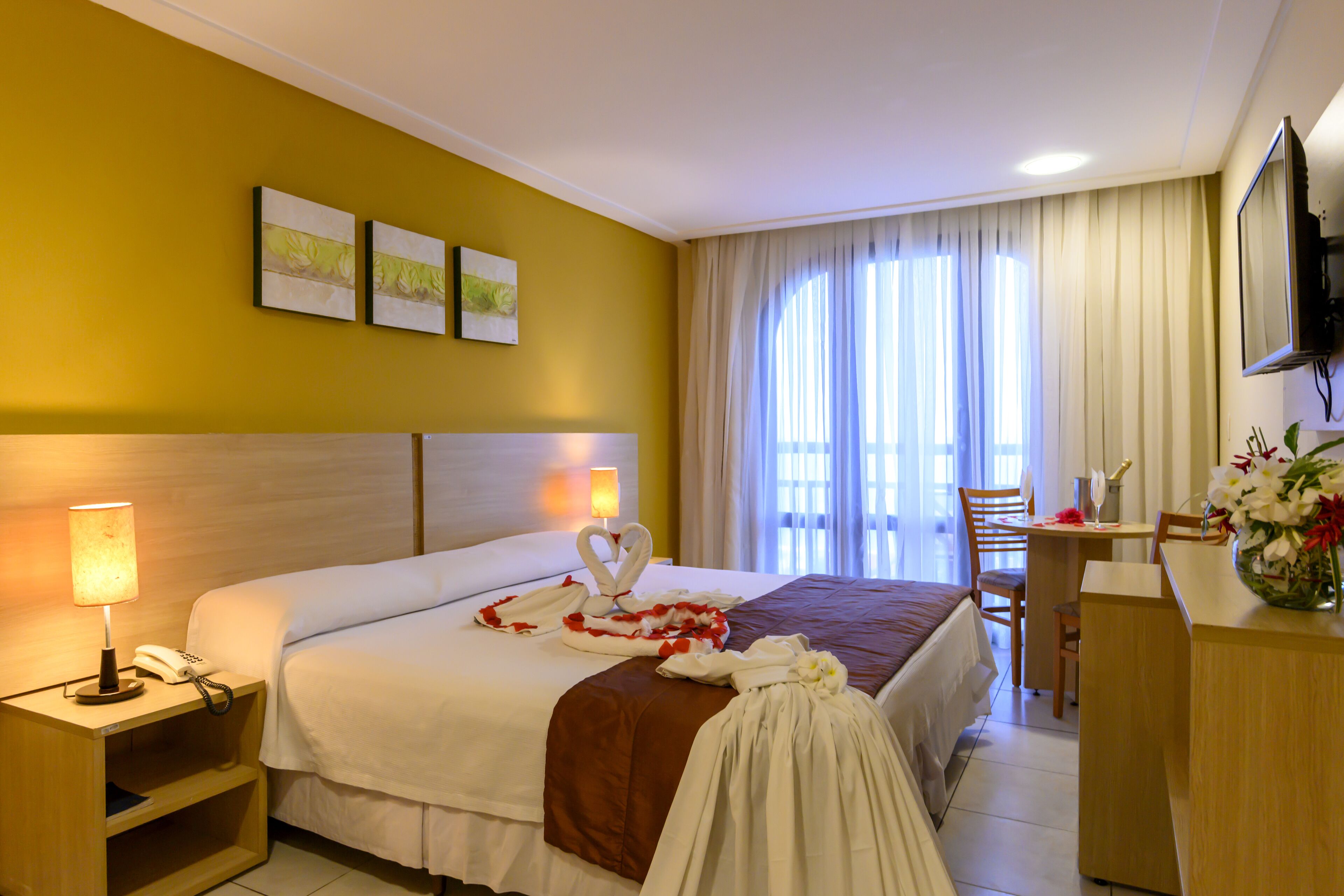 Une chambre d’hôtel comprenant un lit, une table de chevet, une lampe et un bureau avec une chaise.