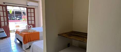A small, clean room with two beds, a refrigerator, and a wooden shelf.
