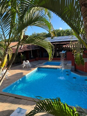 Una piscina techada, una piscina al aire libre, sombrillas