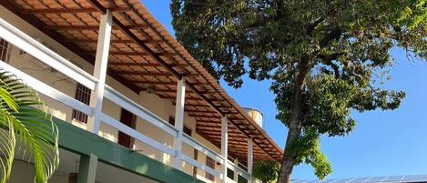 A two-story building with a brown tiled roof and white railings.