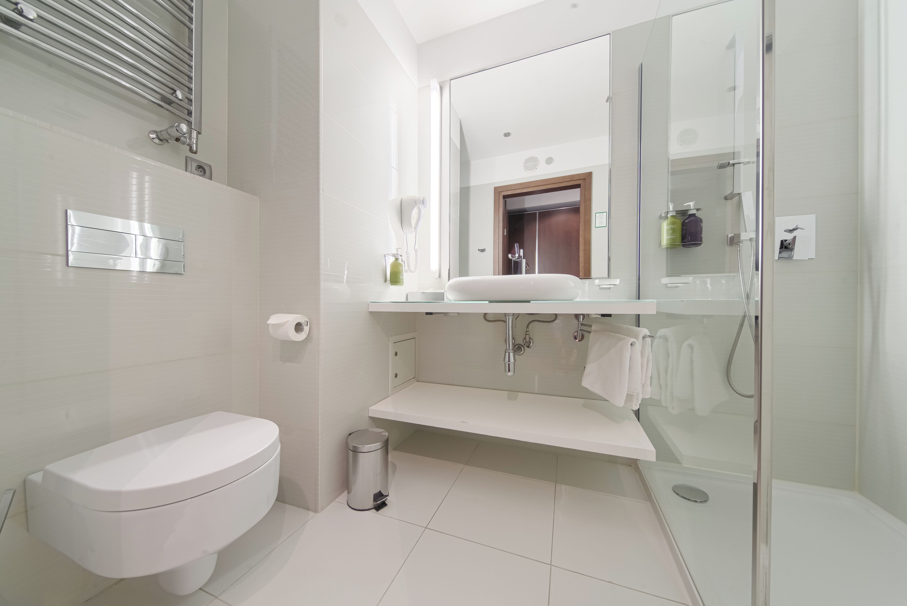 A modern bathroom with a toilet, sink, and glass shower enclosure.