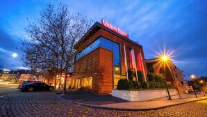 A hotel with a modern design, a prominent sign, and a cobblestone street. - Qubus Hotel Bydgoszcz (Bydgoszcz)