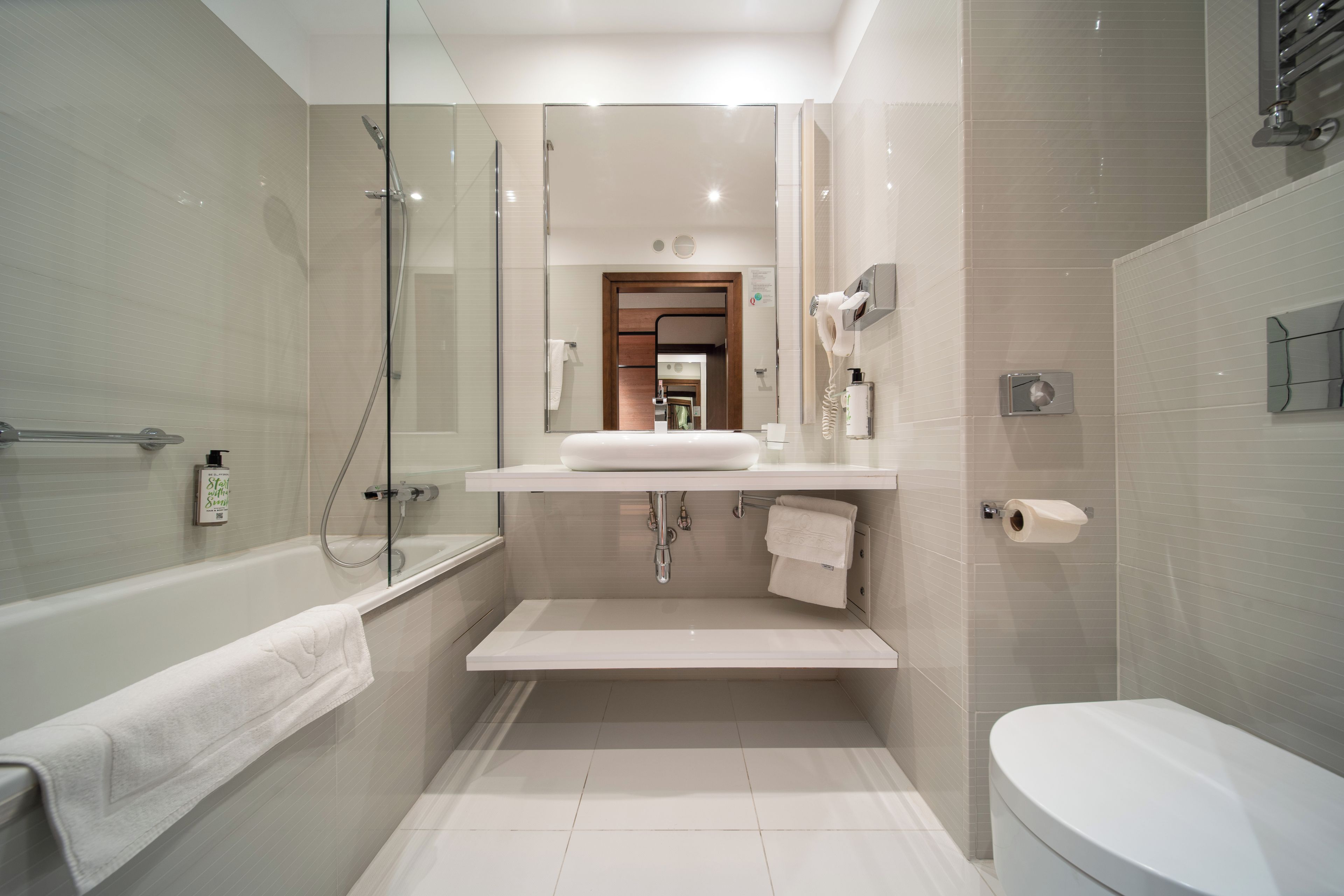 A modern bathroom with a glass-enclosed shower, a white sink, and a toilet.