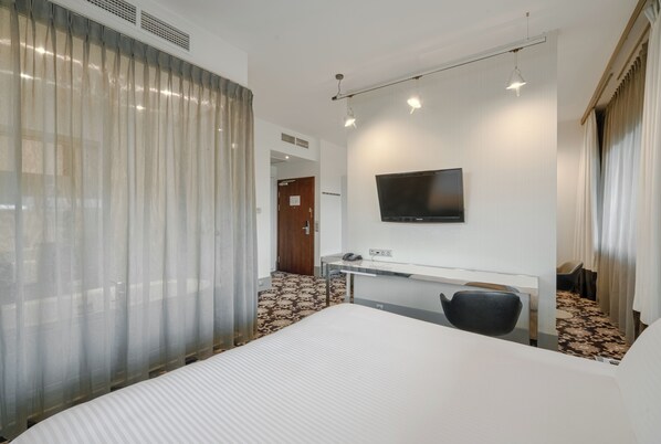 A hotel room with a bed, a desk, a chair, a television, and a window with curtains. - Qubus Hotel Bydgoszcz (Bydgoszcz)
