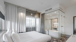 A hotel room with a large bed, a glass-enclosed shower, and a desk. - Qubus Hotel Bydgoszcz (Bydgoszcz)