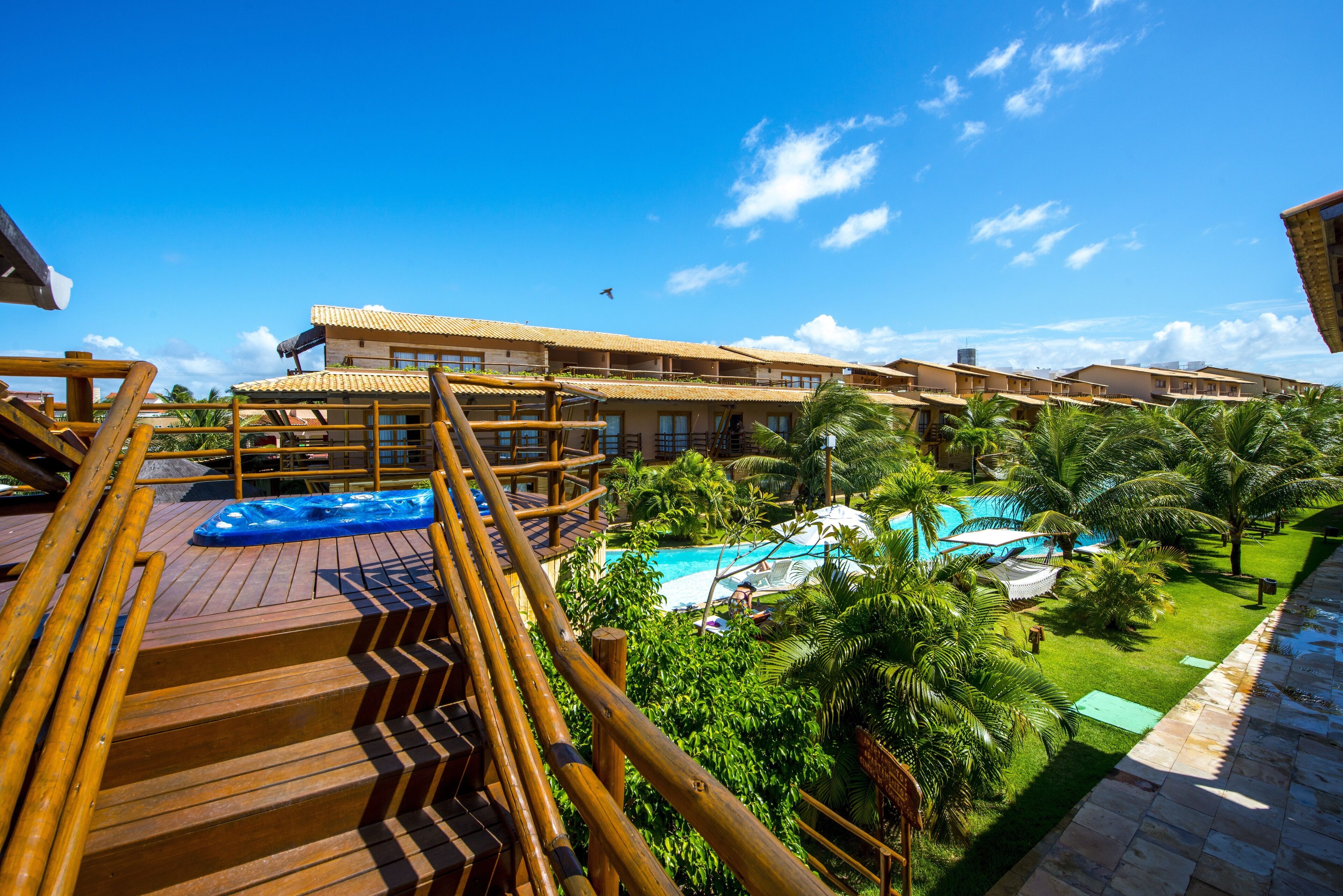A resort with a wooden deck, a swimming pool, and lush greenery.